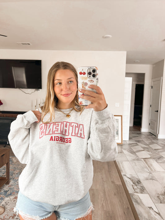 Person wearing a gray sweatshirt with red text in a living room.
